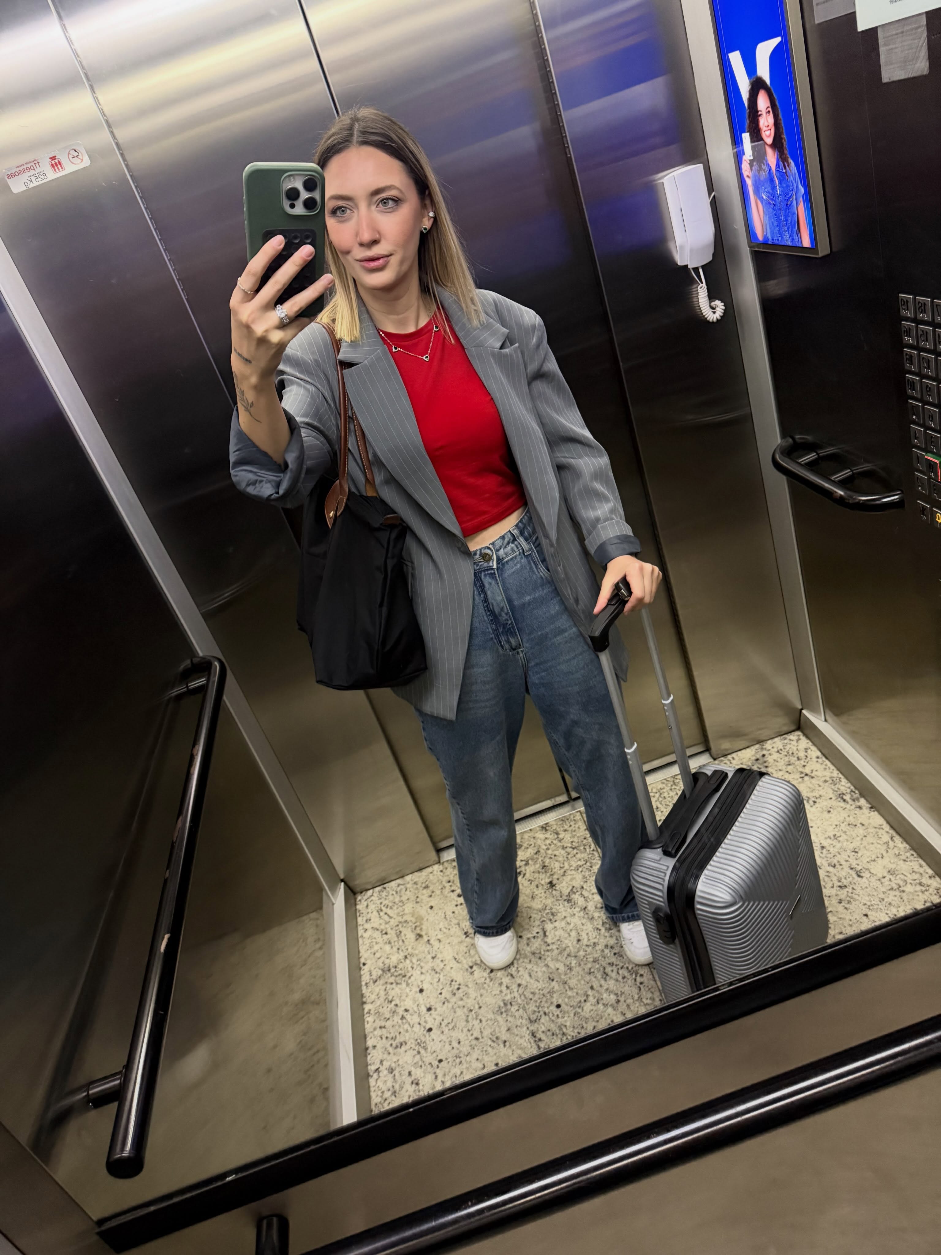 Sylvia Fraquete usando blazer cinza, blusa vermelha e jeans